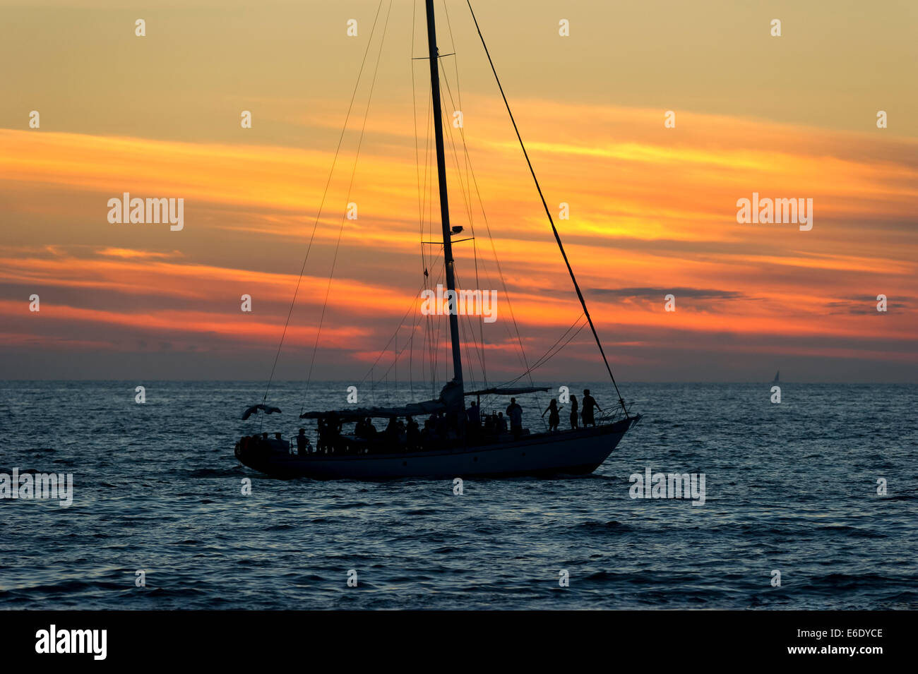 Un voilier navigue plein de gens dans le coucher du soleil. Banque D'Images