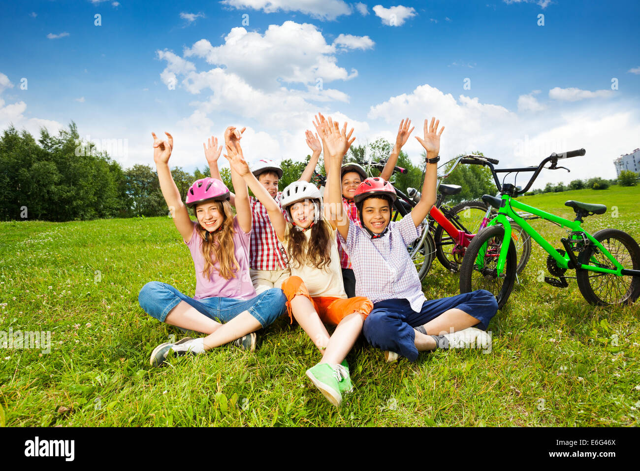 Enfants heureux dans l'herbe sur les casques avec hands up Banque D'Images