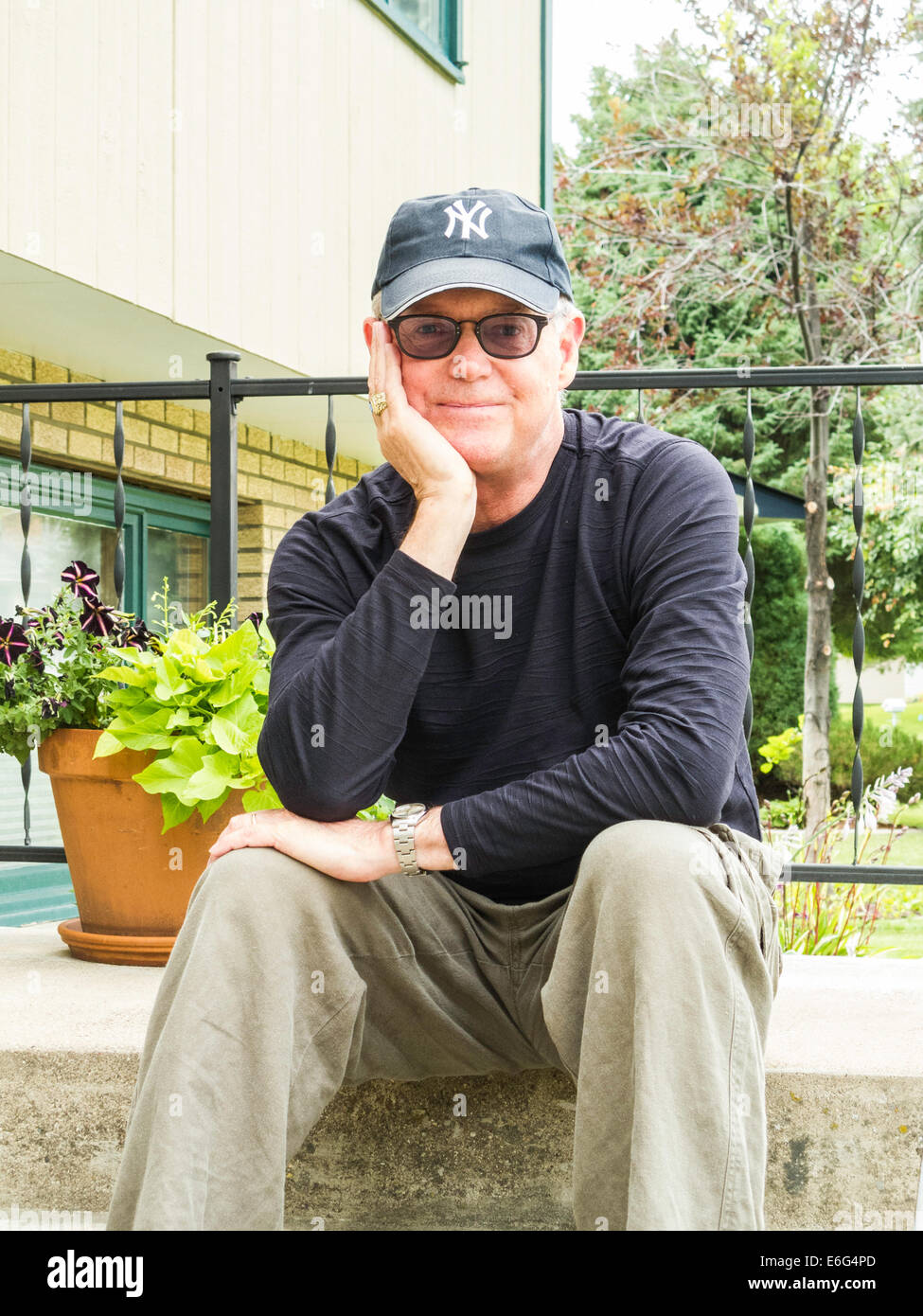 Senior homme est assis sur le porche de la maison de banlieue, USA Banque D'Images