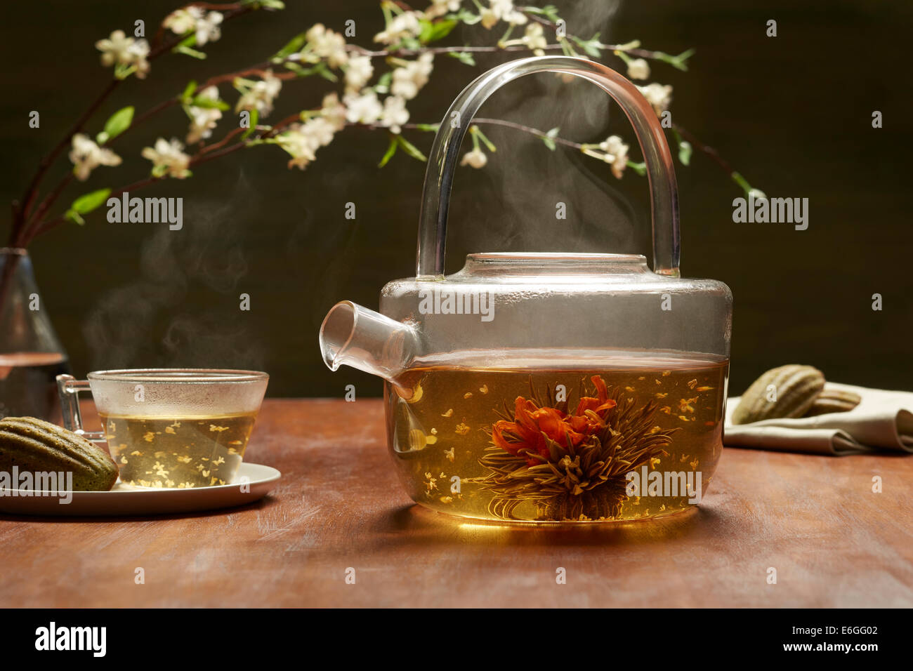La floraison du thé dans une théière en verre steamy, accompagné par madelines matcha. Banque D'Images