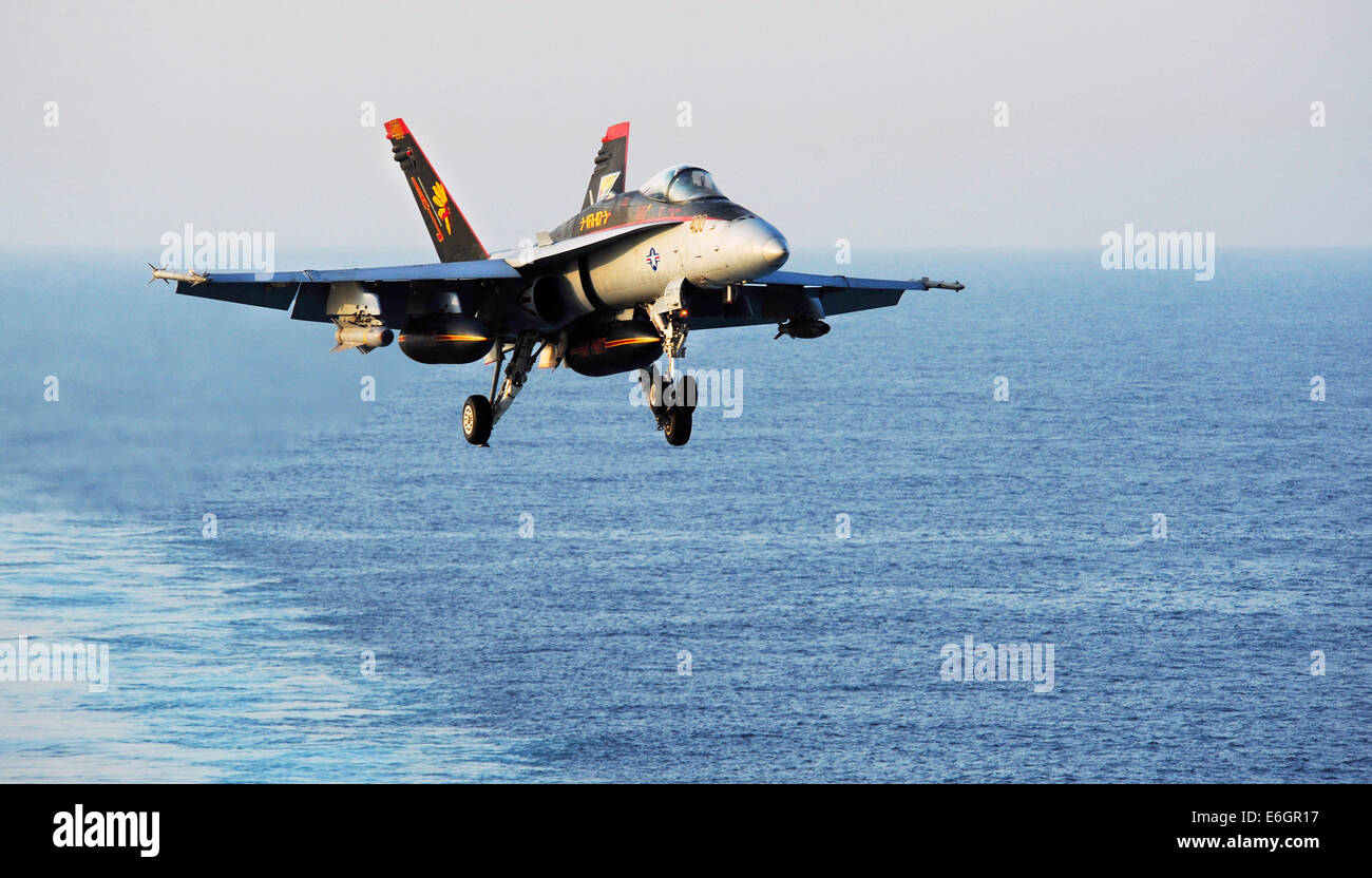 La Marine américaine F/A-18C Hornet se prépare à atterrir sur le pont d'envol du porte-avions USS George H. W. Bush après une mission à l'appui de l'armée iraquienne le 12 août 2014. Le président Obama a autorisé les frappes aériennes ciblées pour protéger le personnel américain de la part des extrémistes connus sous le nom de l'État islamique en Irak et au Levant. Banque D'Images