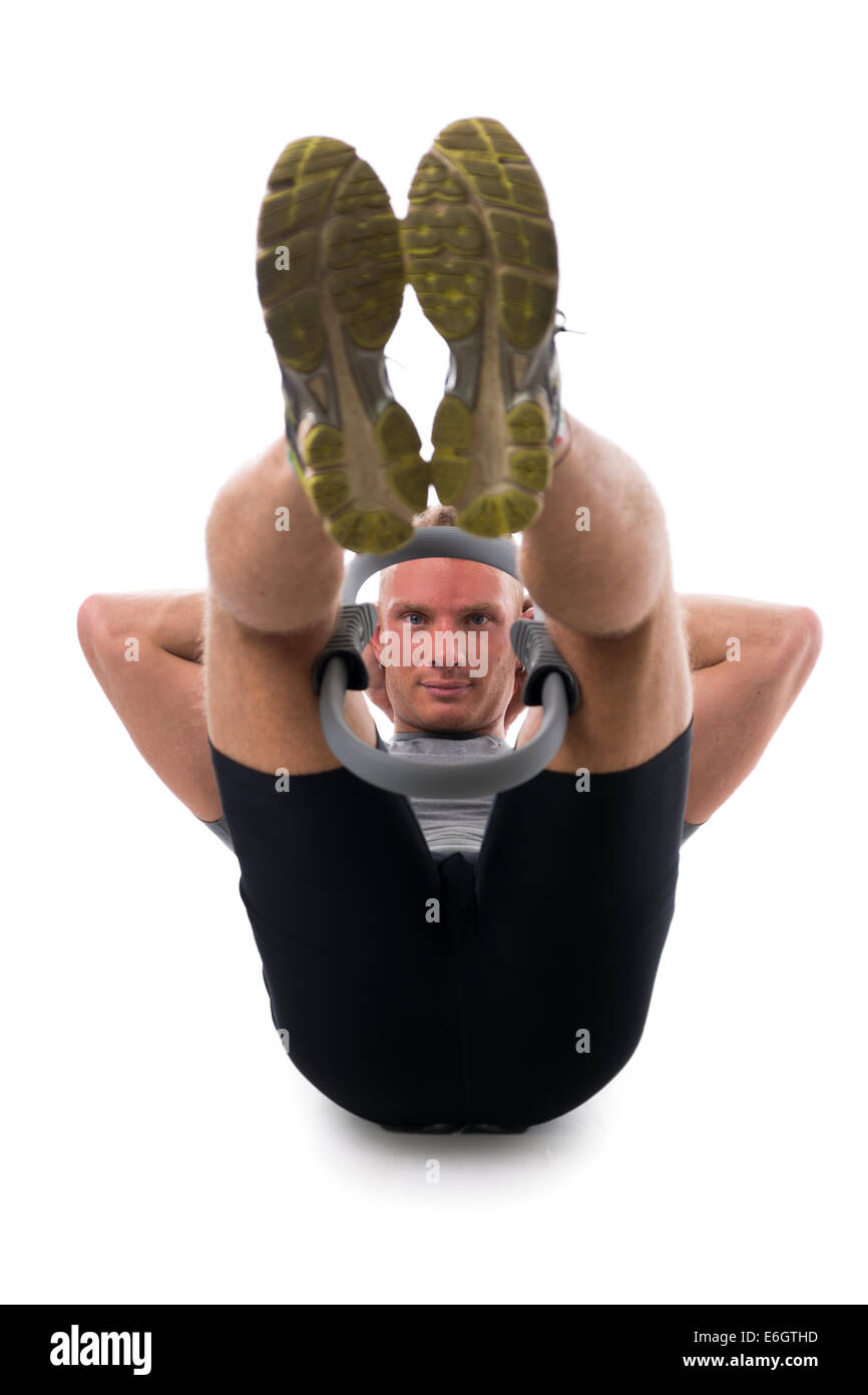 Jeune homme musclé s'entraîner avec le Pilates ring entre les jambes et les genoux, isolated on white Banque D'Images