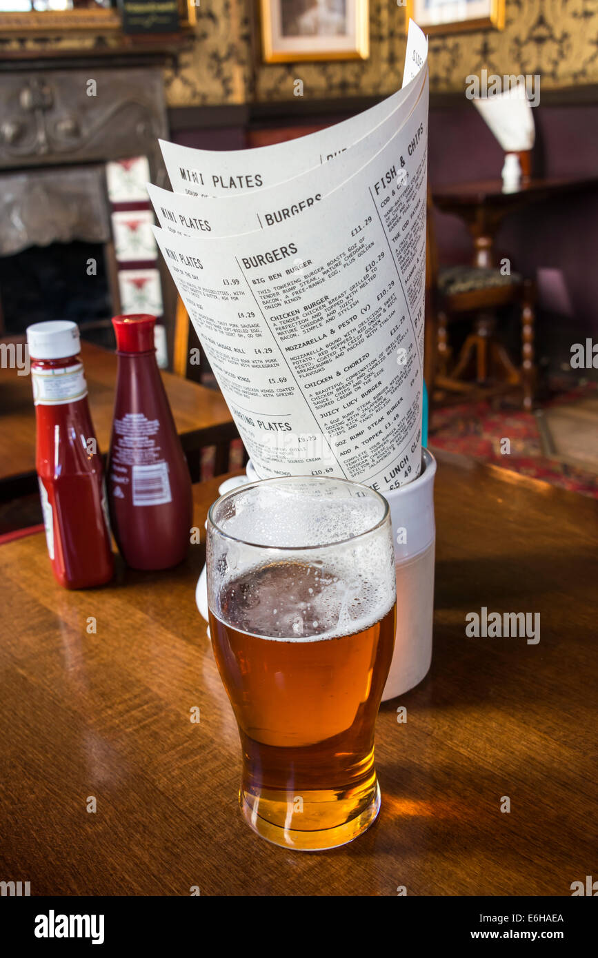 Une pinte de bière en face de menus de déjeuner dans un pub anglais traditionnel Banque D'Images