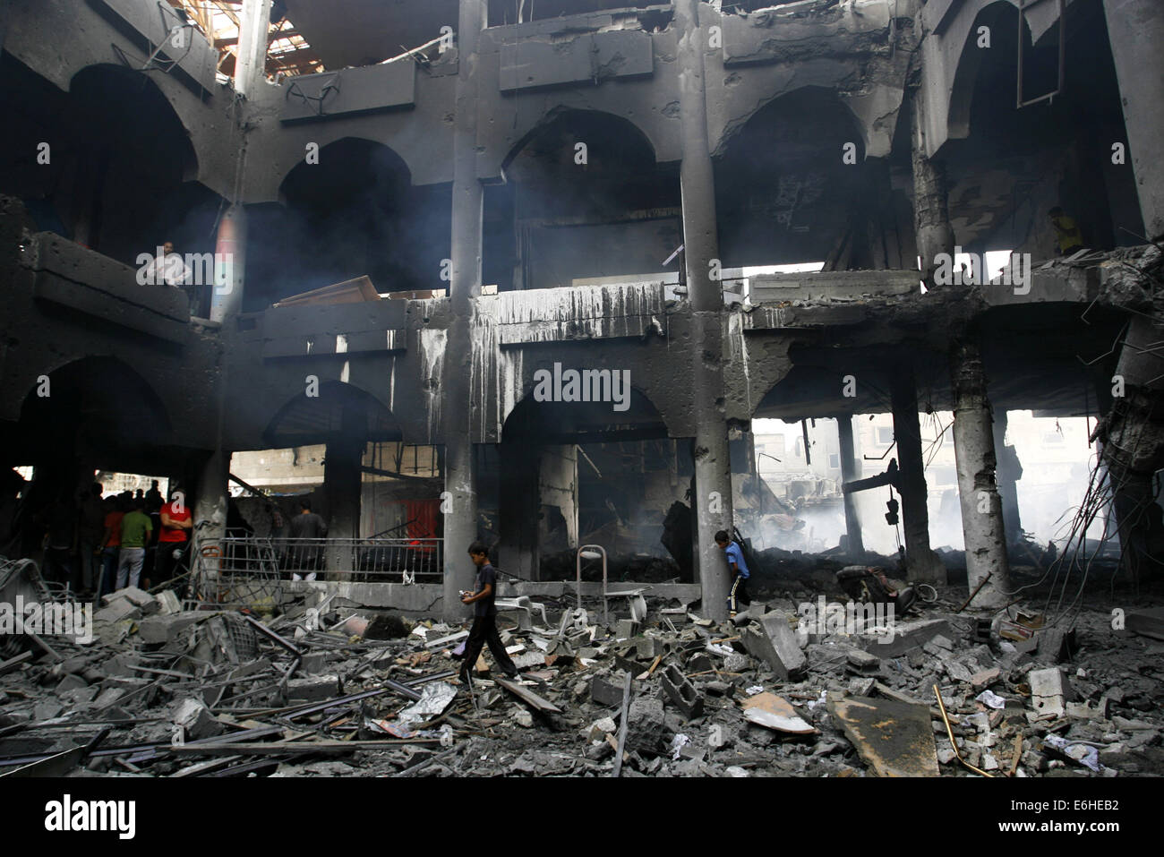 Rafah, bande de Gaza, territoire palestinien. 24 août, 2014. Palestiniens regarder les restes d'un centre commercial, qui selon des témoins a été touché par une frappe aérienne israélienne le samedi à Rafah, dans le sud de la bande de Gaza, le 24 août 2014. L'Égypte a appelé Israël et les Palestiniens le samedi à mettre un terme aux hostilités et à reprendre les pourparlers de paix, mais les deux parties tenues, y compris d'une frappe aérienne israélienne qui a détruit une tour résidentielle bloc dans le centre de la ville de Gaza. Des militants du Hamas a tiré des roquettes sur Israël, frapper le sud de la ville de Beer-Sheva, où deux personnes ont été blessés, a annoncé la police. Ano Banque D'Images