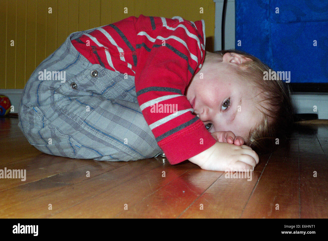 Un petit garçon recroquevillé sur le plancher des soies Banque D'Images