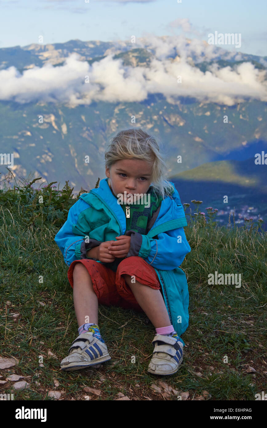 Une jeune fille assise sur un sol et repose après une randonnée de la colline, nuages de fond, Monte Altissimo, Alpes, Italie Banque D'Images