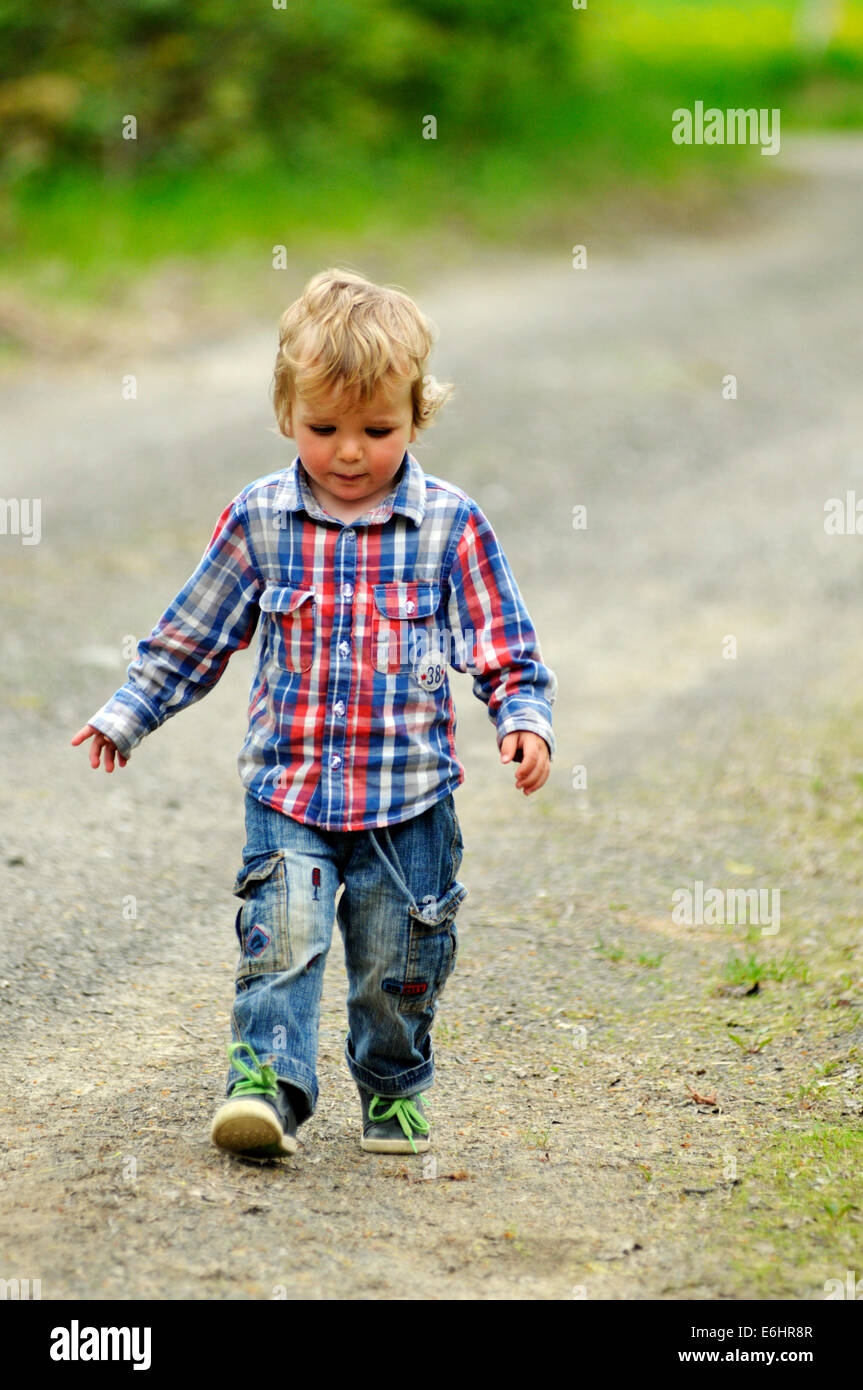 Un petit garçon marche dans un lecteur de gravier Banque D'Images