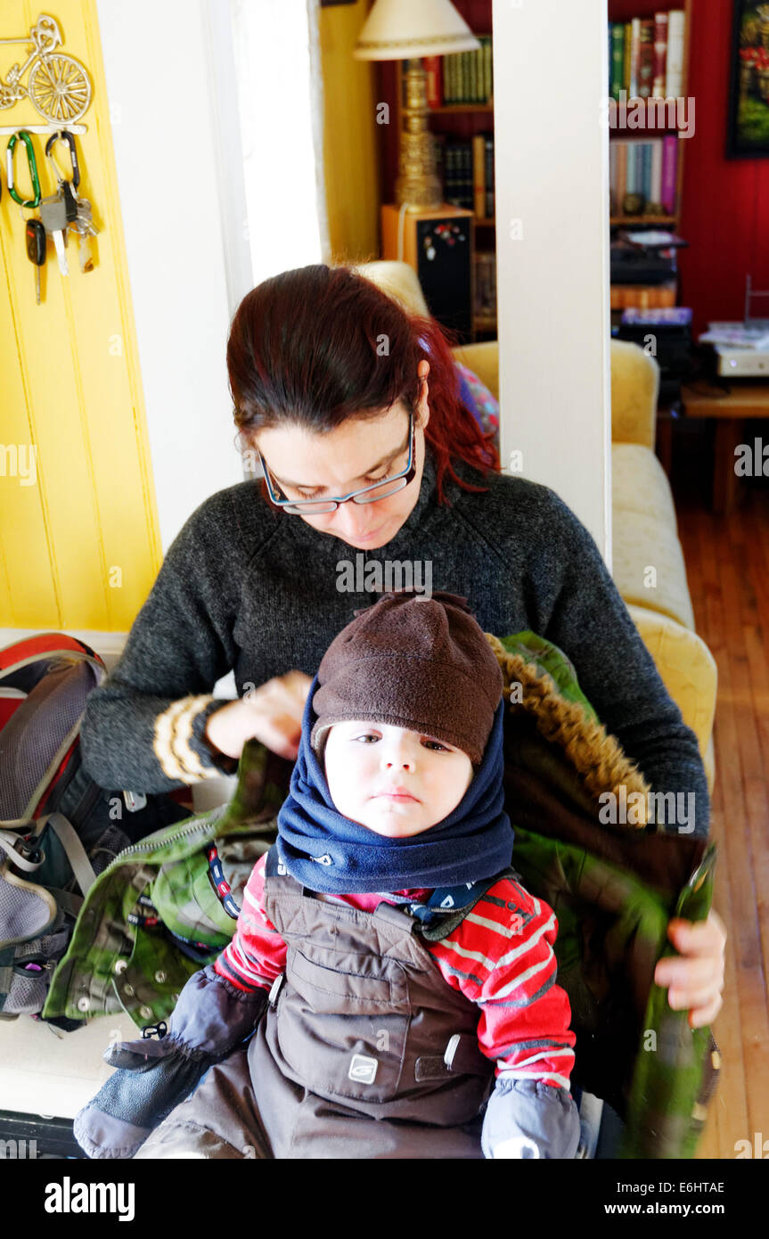 Une mère s'habiller son fils d'aller à l'extérieur en hiver au Québec, l'enfant portant un chapeau, gants, écharpe Banque D'Images
