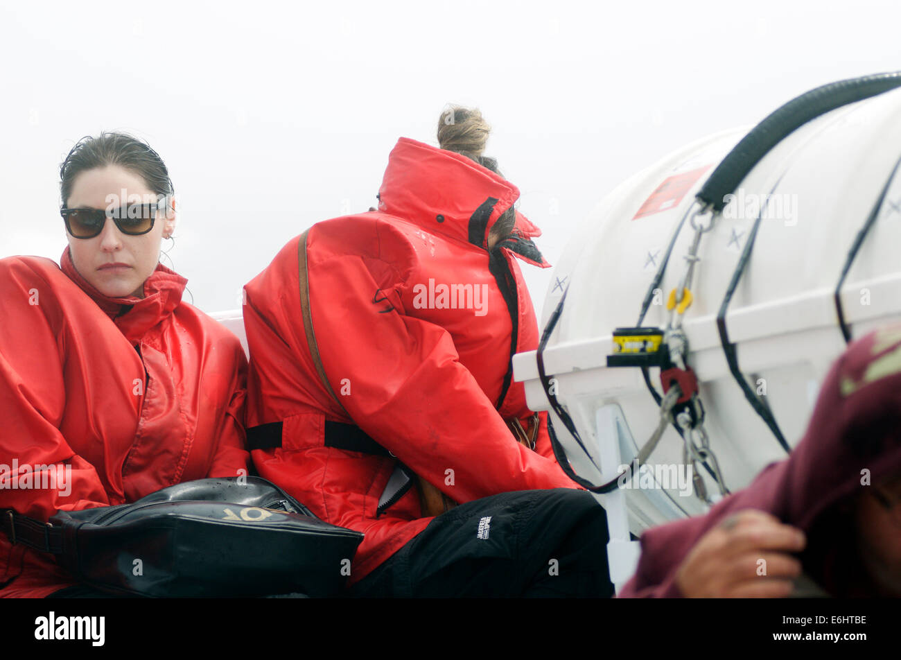 Deux femmes misérable essaie de cacher le gel cold spray sur un bateau d'observation des baleines sur le Saint-Laurent Banque D'Images