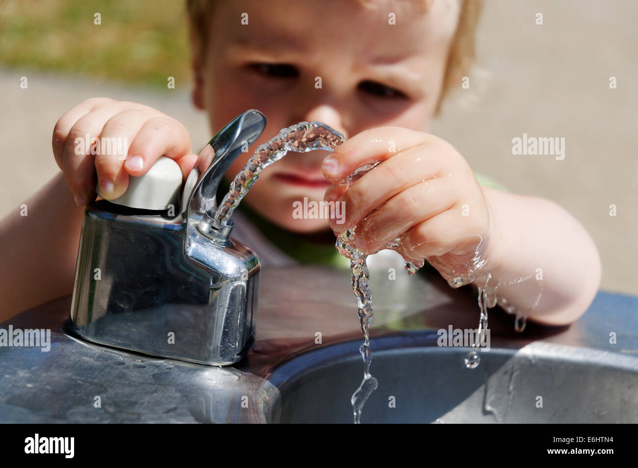 Un jeune garçon jouant avec une fontaine d'eau potable Banque D'Images