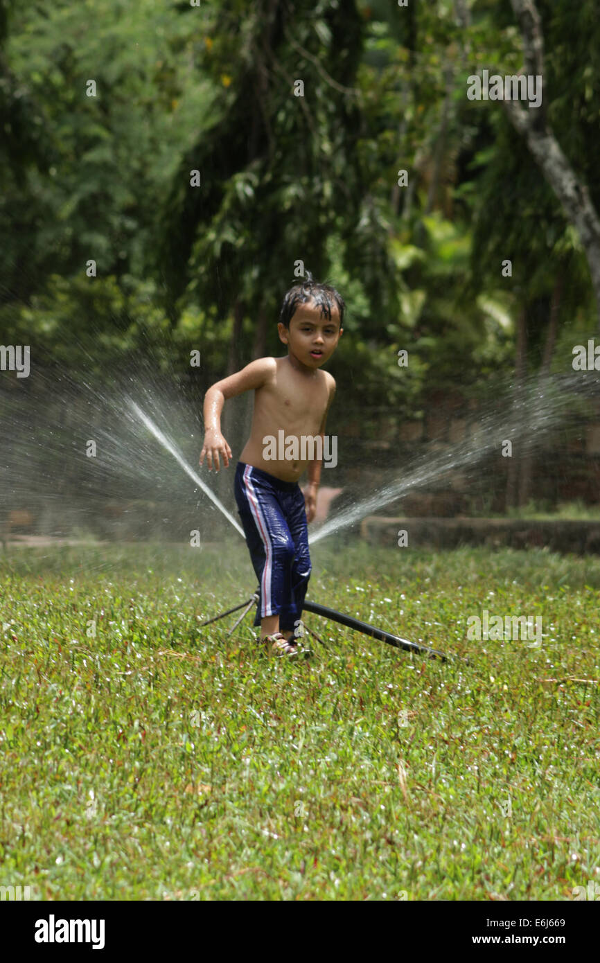 Petit garçon jouer dans le parc avec water sprinkler Banque D'Images