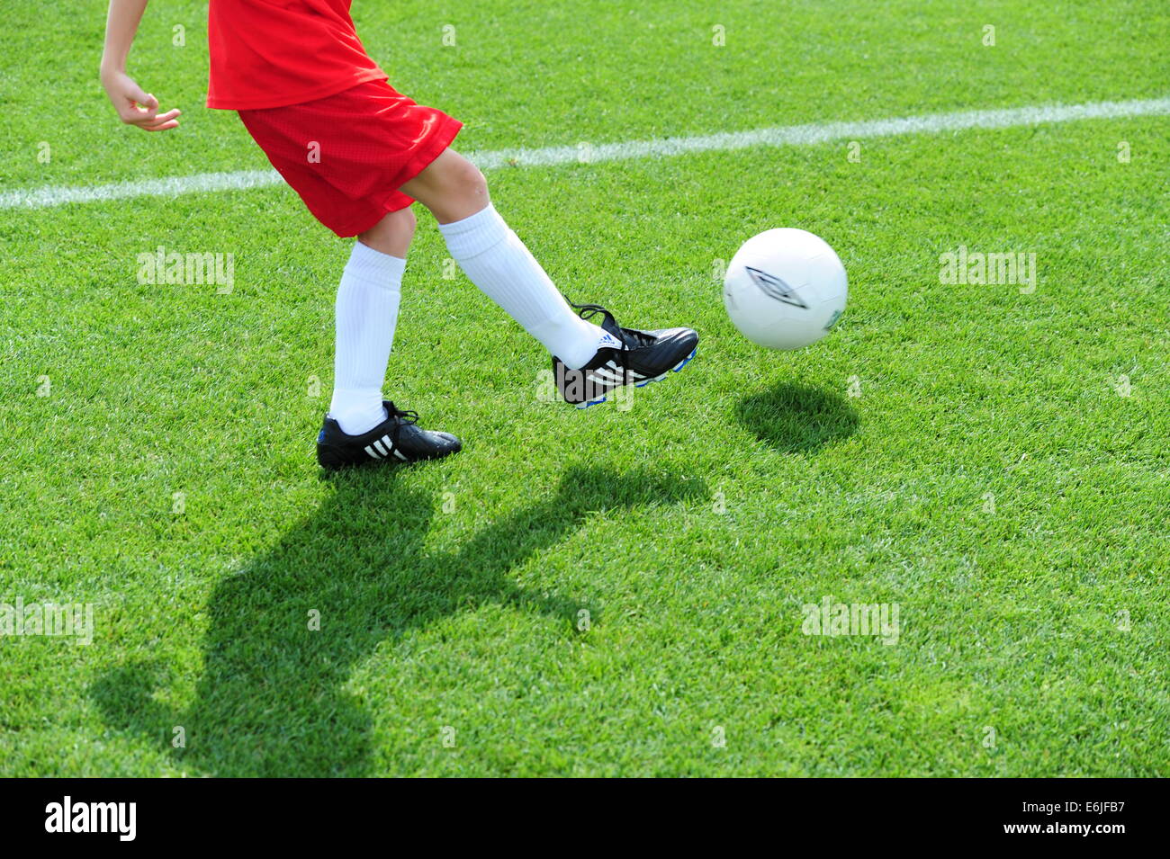 Boy 9 10 11 jouant au football sur terrain de soccer futball grassy field Banque D'Images