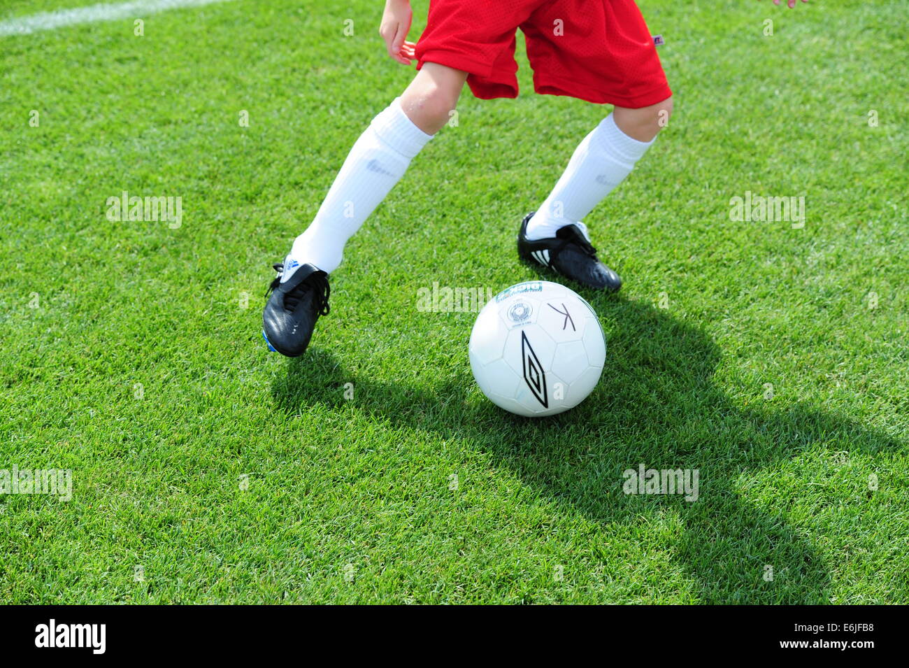Boy 9 10 11 jouer au football futbol soccer pitch on grassy field Banque D'Images