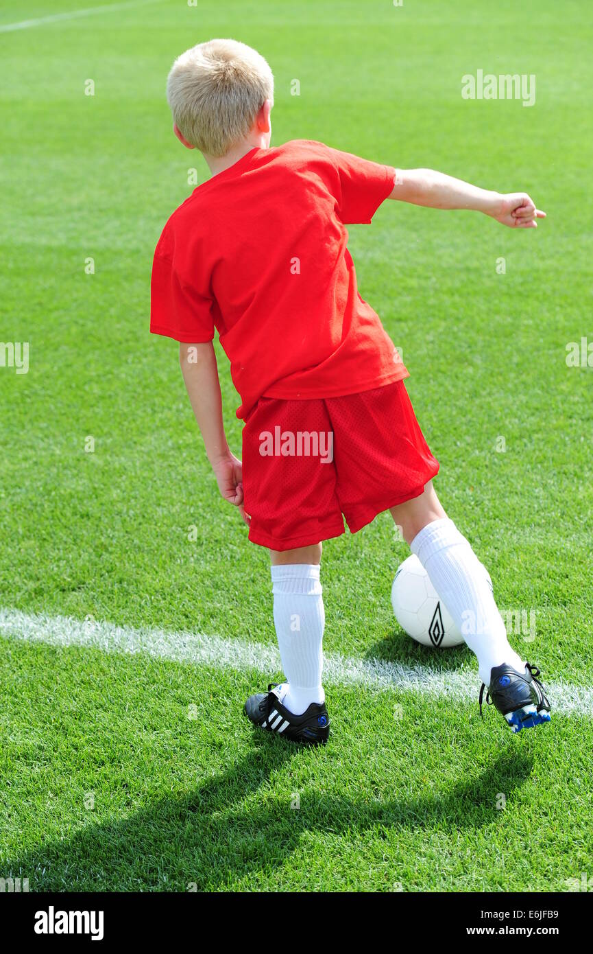 Boy 9 10 11 jouer au football futbol soccer pitch on grassy field Banque D'Images