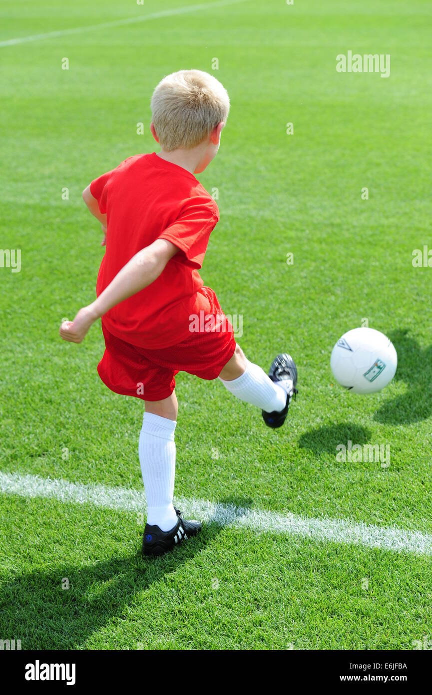 Boy 9 10 11 jouer au football futbol soccer pitch on grassy field Banque D'Images