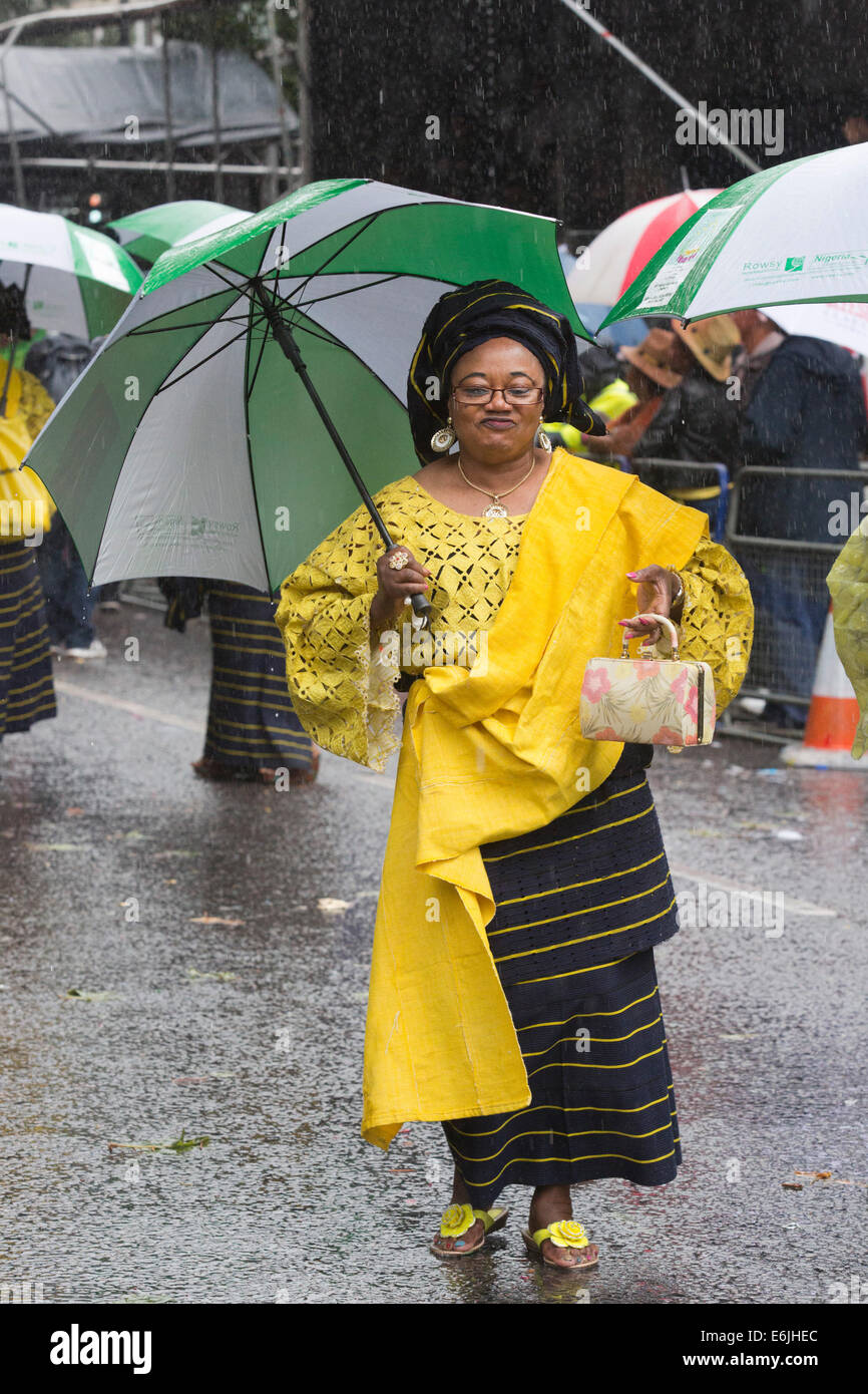 Londres, Royaume-Uni. 25 août 2014. Certains participants y la parade in Style - avec l'aide de grands parasols. Les visiteurs et les participants du carnaval de Notting Hill 2014 Bank Holiday parade lundi s'est imbibé de leur peau, mais la météo n'a pu refroidir les fêtards esprit - bien qu'un grand nombre de spectateurs sont restés à l'écart. Photo : Nick Savage/Alamy Live News Banque D'Images