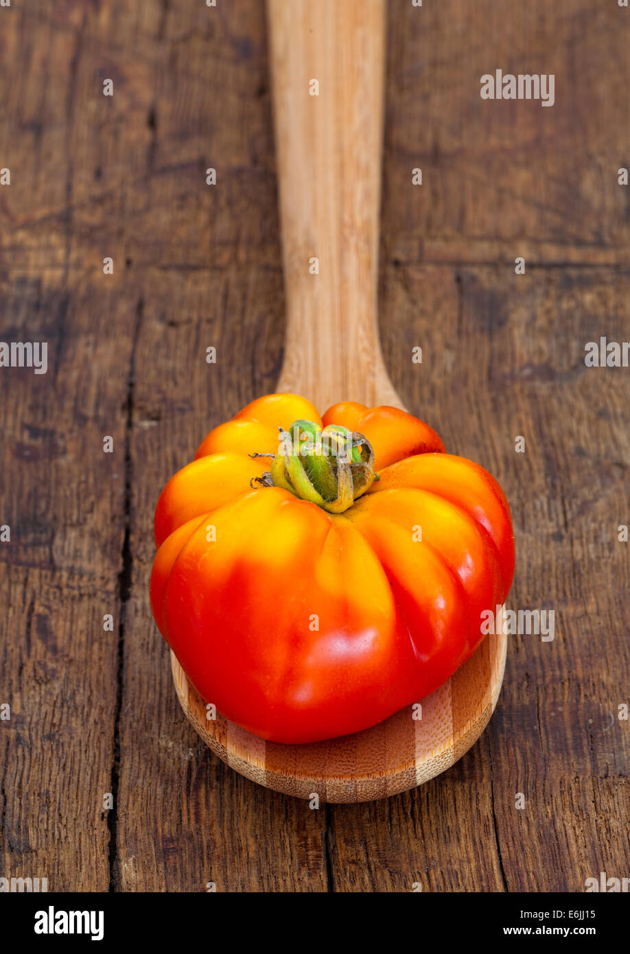 Tomates mûres à partir de leur propre jardin sur cuillère en bois sur une vieille planche à découper rustique dans un style champêtre Banque D'Images