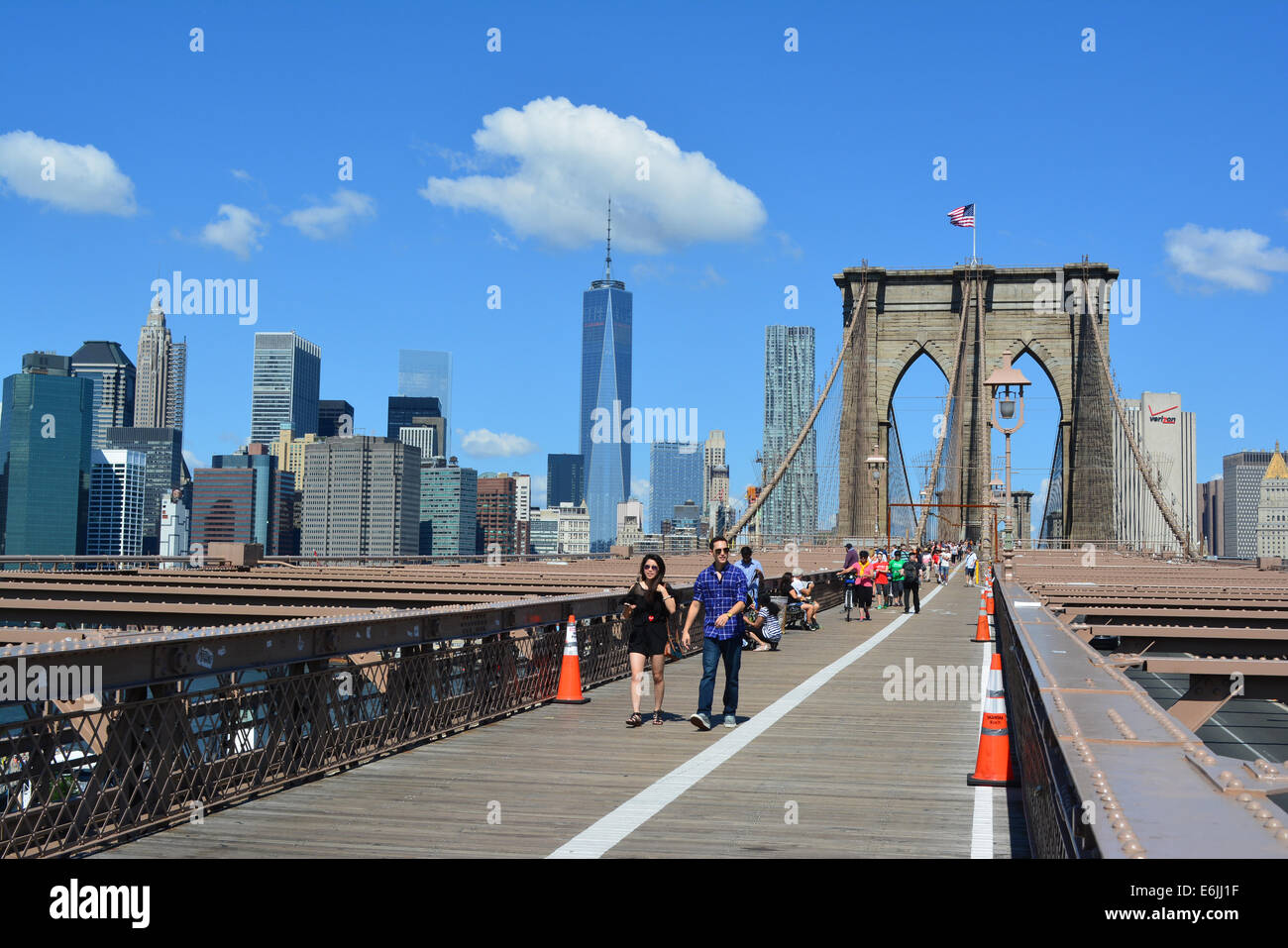 Les personnes qui franchissent le pont de Brooklyn avec le Lower Manhattan skyline en arrière-plan. Banque D'Images