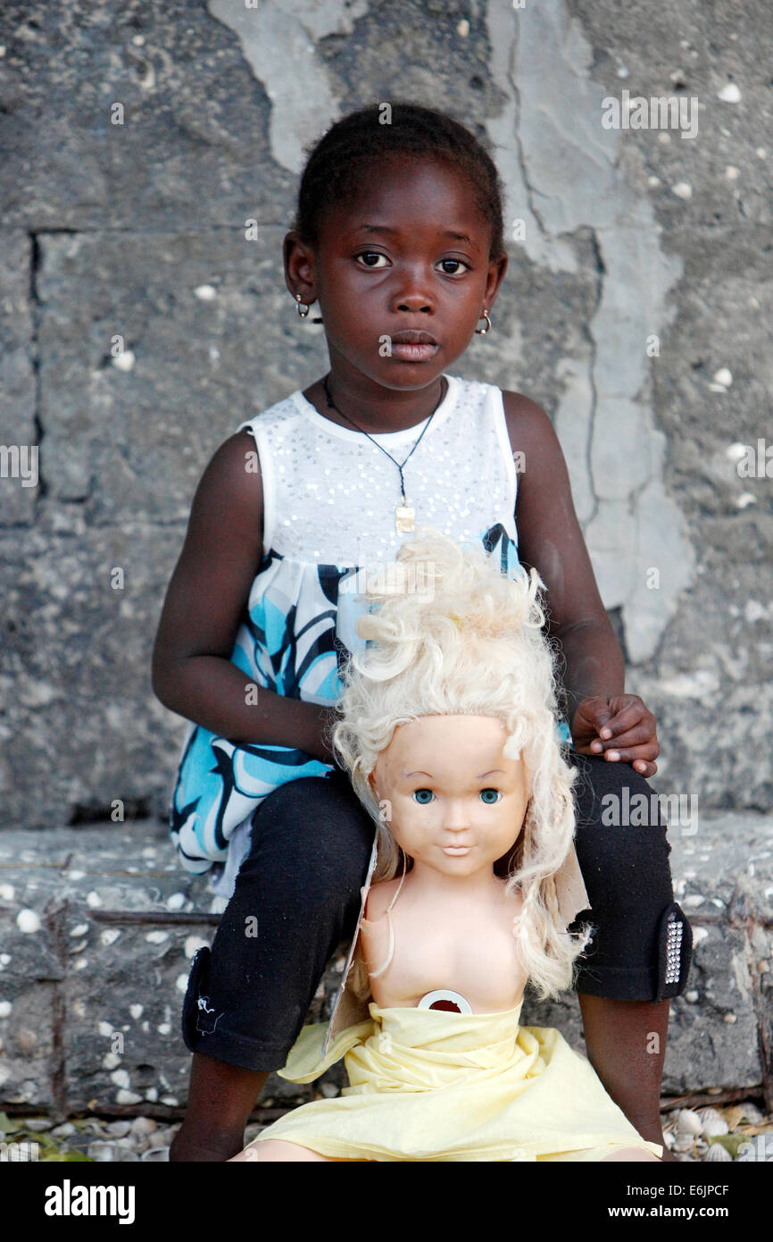 Fille noire avec sa poupée blanche avec des cheveux blonds. Fadiouth, Sénégal Banque D'Images