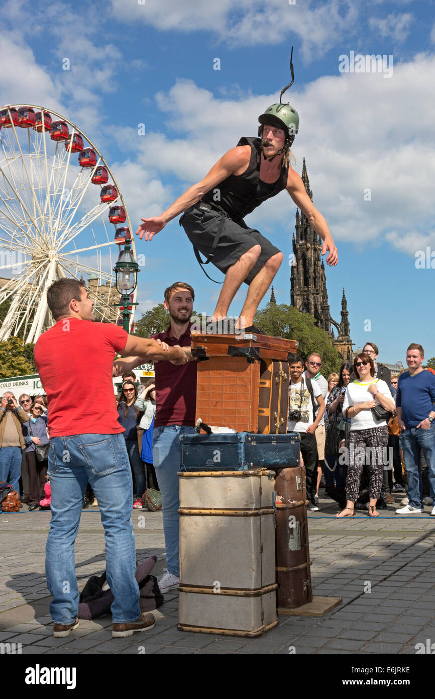 Acrobat performing son équilibre, avec l'aide de deux hommes de l'auditoire, à la butte, Edinburgh Fringe Festival. Banque D'Images