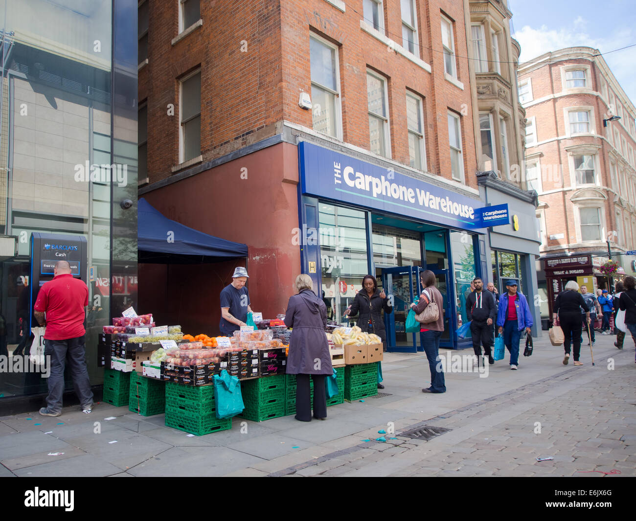 Décrochage du marché de l'alimentation traditionnelle à côté d'un distributeur automatique moderne et une Carphone Warehouse sur Market Street dans le centre-ville de Manchester Banque D'Images