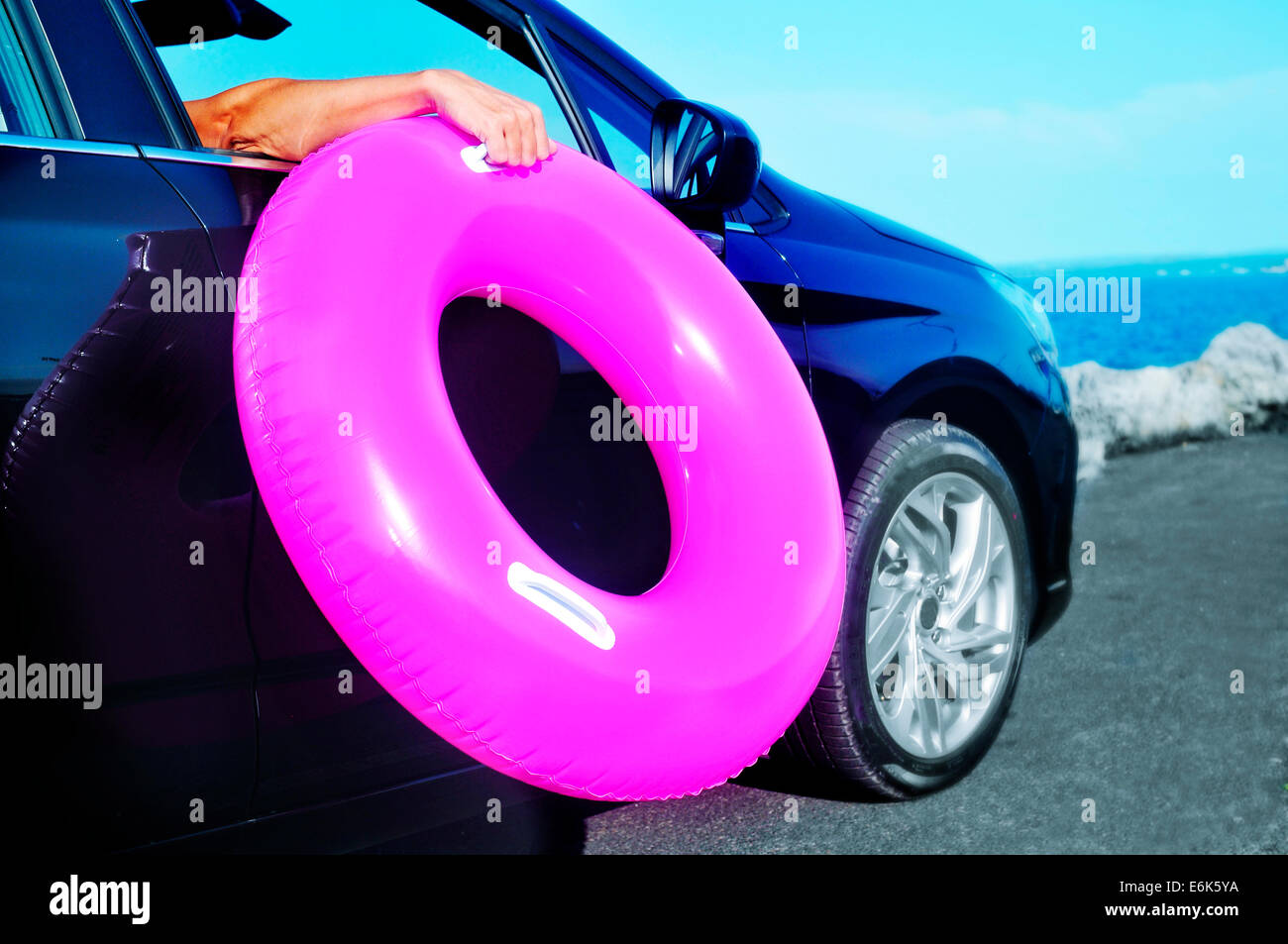 Jeune homme tenant un anneau de natation à l'extérieur de la fenêtre d'une voiture Banque D'Images