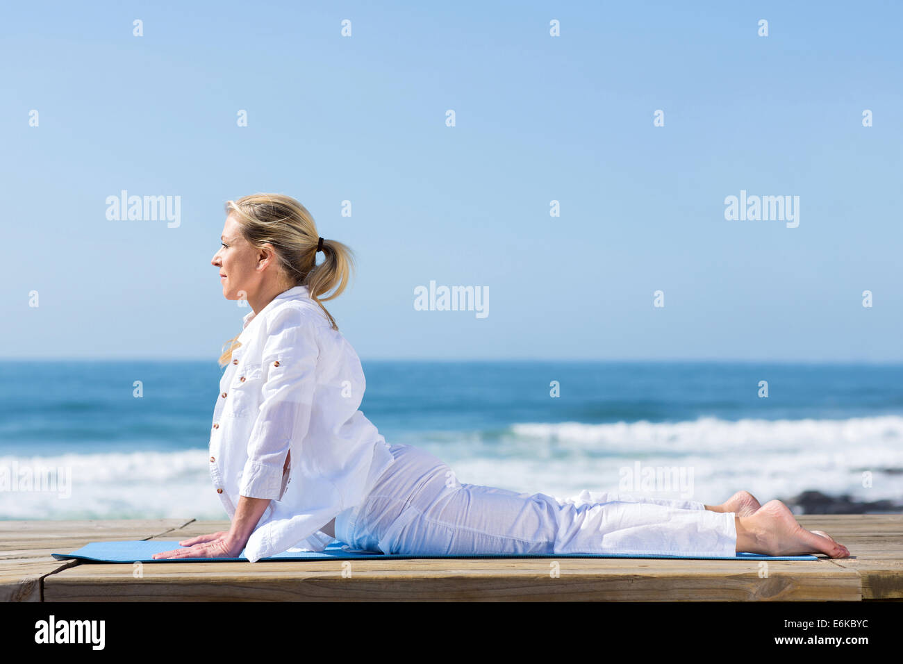 Femme mature cobra yoga position on beach Banque D'Images