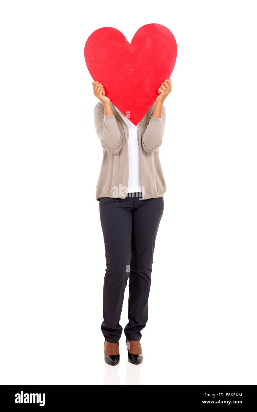 Jeune femme cachant son visage derrière en forme de coeur rouge isolé sur fond blanc Banque D'Images