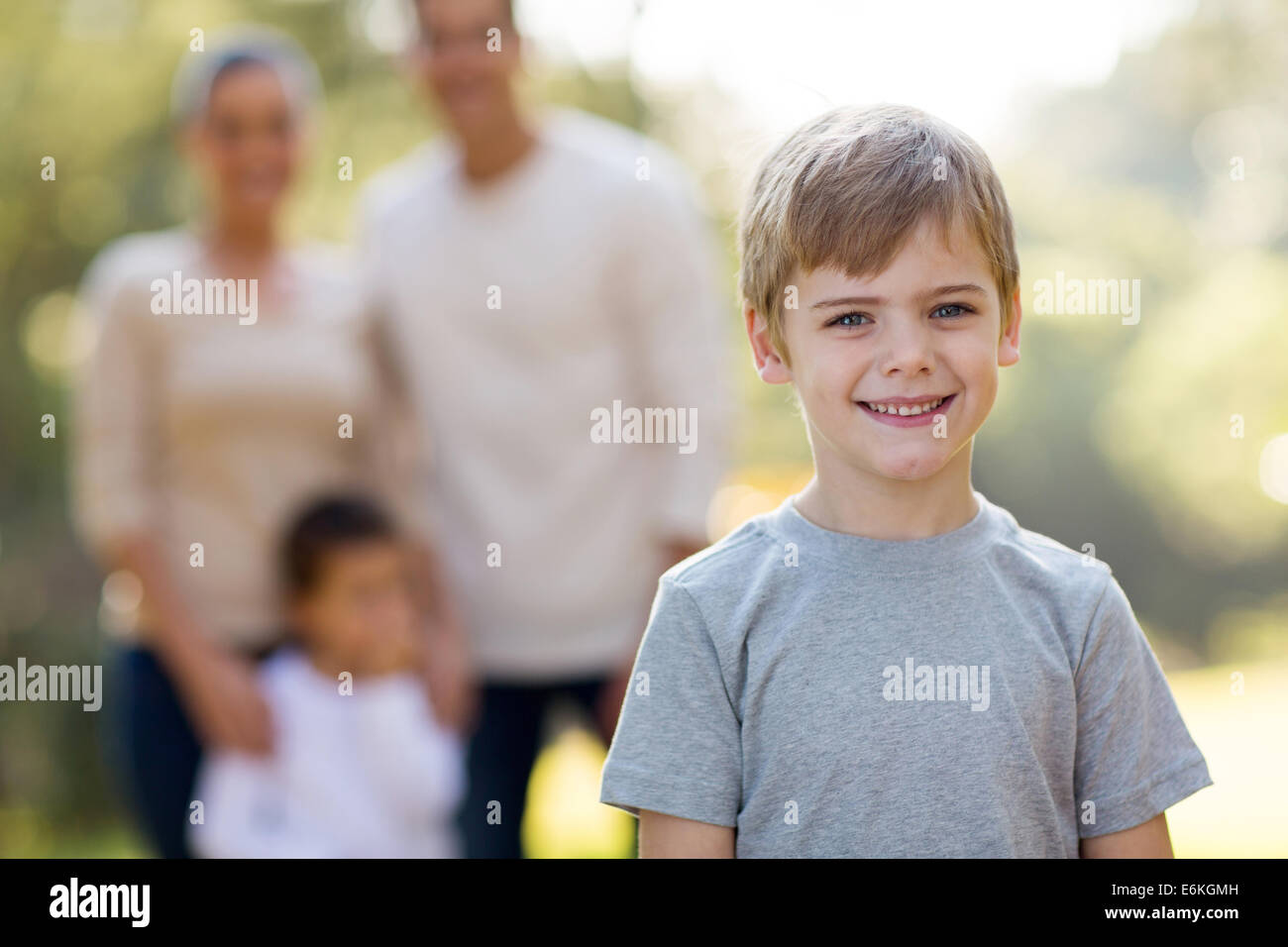 Adorable petit garçon en face de famille en plein air Banque D'Images