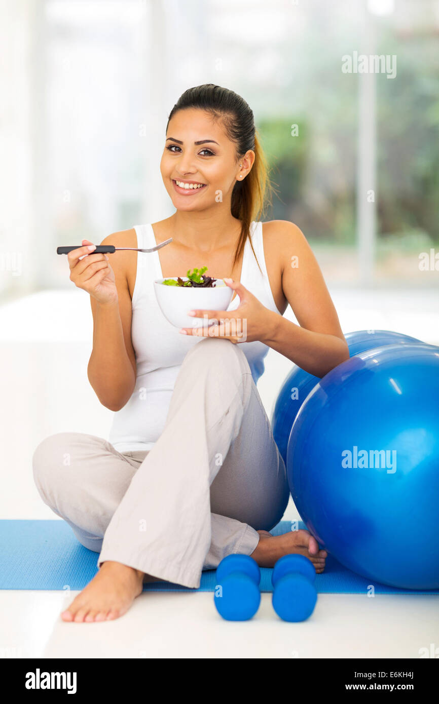 Happy woman enjoying fresh salade saine sitting on exercise mat Banque D'Images