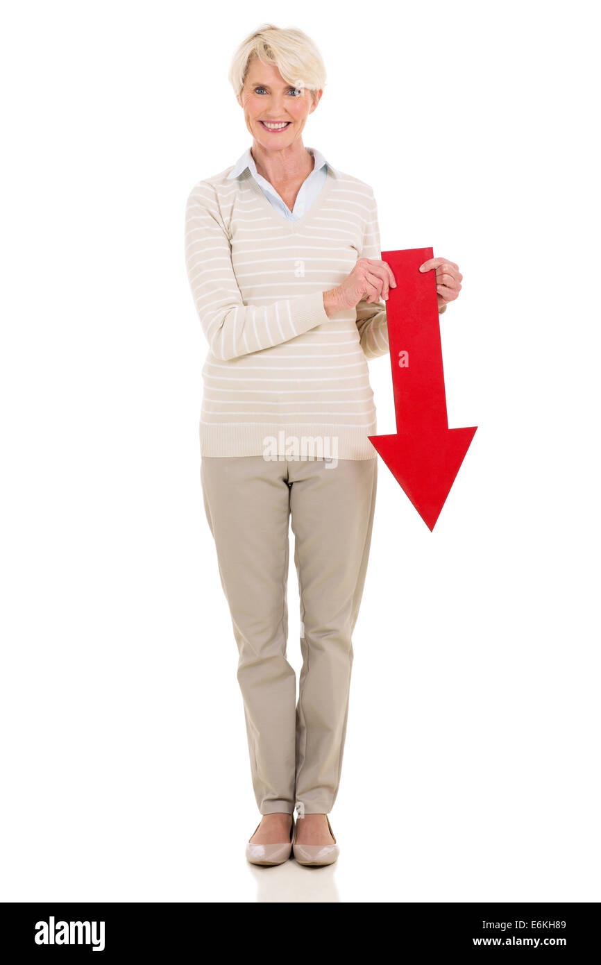 Belle senior woman holding flèche rouge pointant vers le bas sur fond blanc Banque D'Images