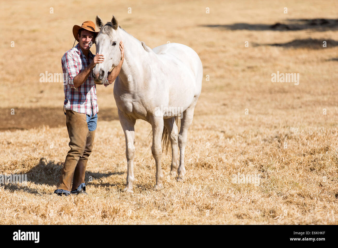Beau cowboy avec un cheval blanc Banque D'Images
