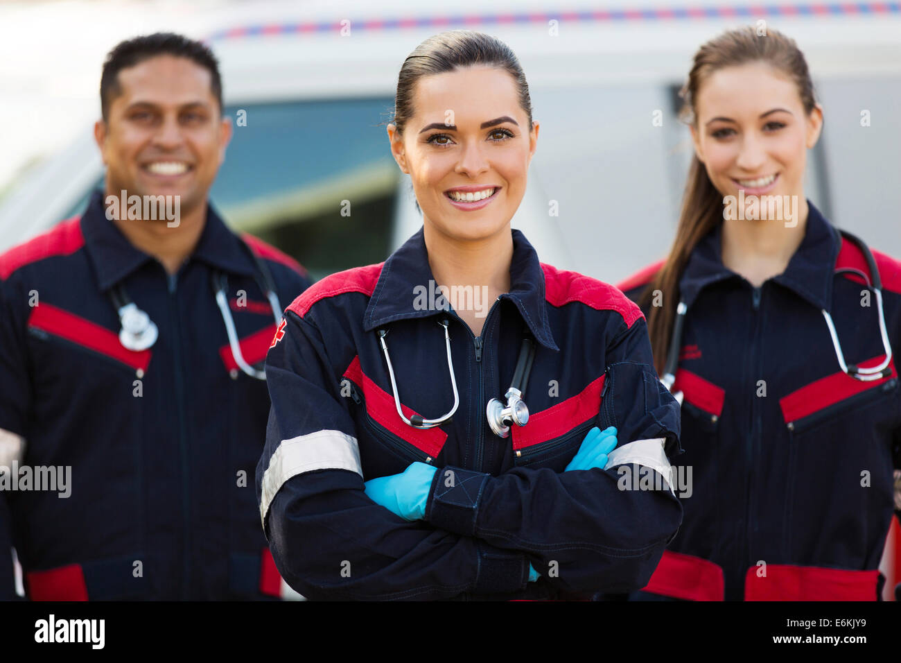 Belle jeune EMT avec des collègues en face de ambulance Banque D'Images
