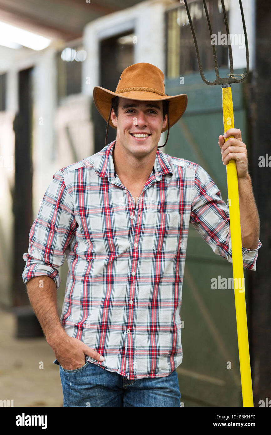 Beau cowboy tenant une fourche en stable Banque D'Images