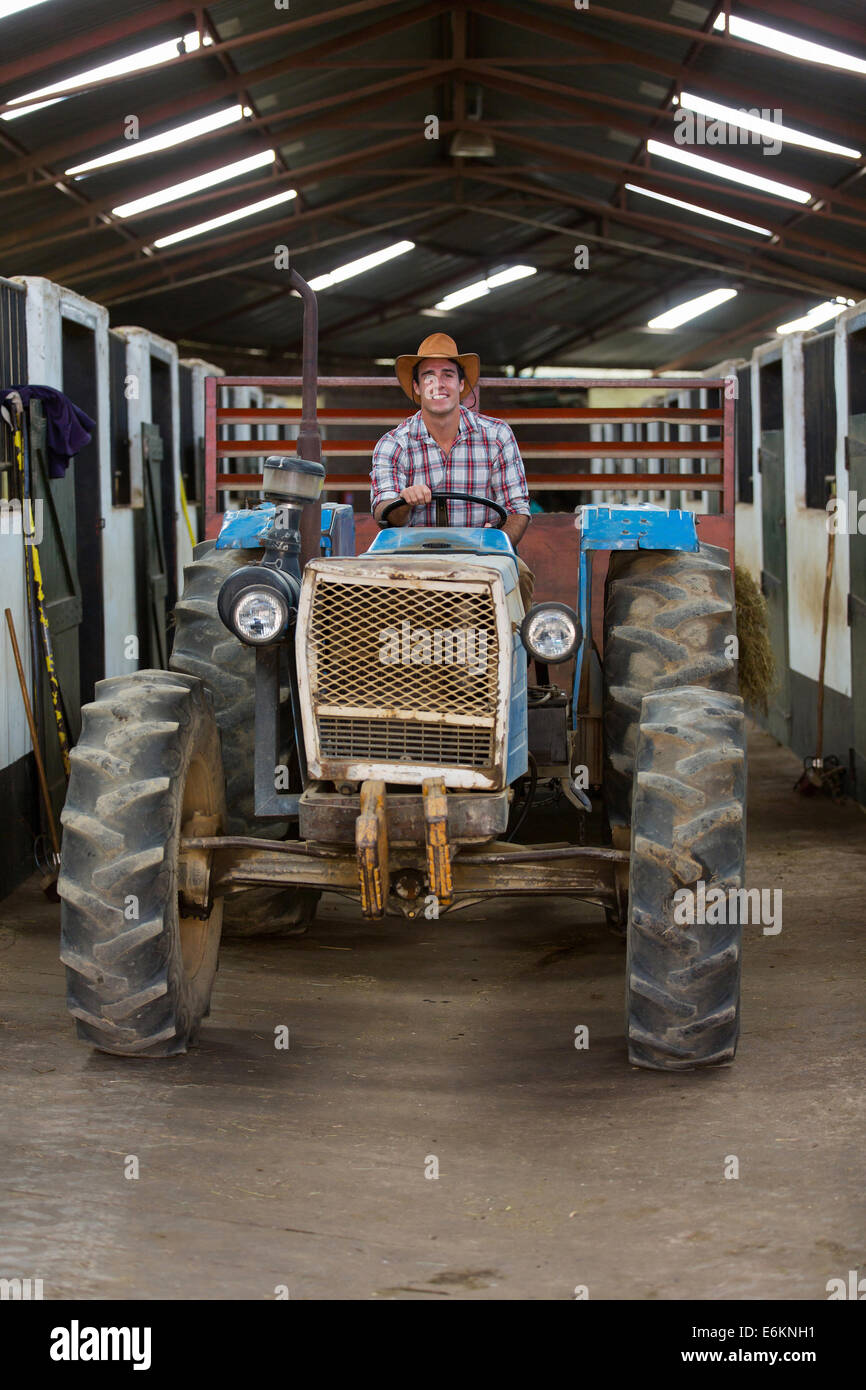 Beau cowboy de la conduite du tracteur à l'intérieur d'équitation Banque D'Images