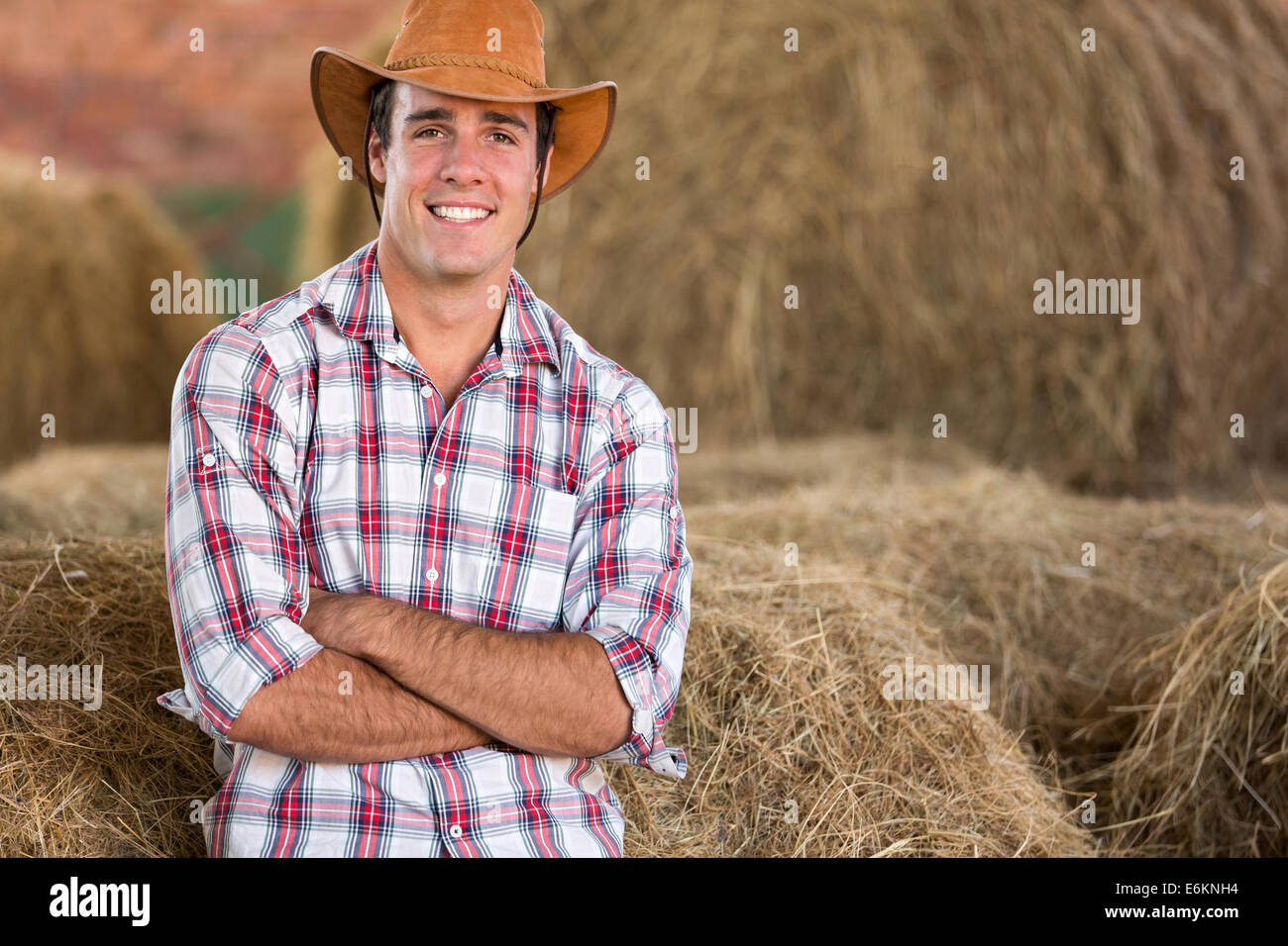 Beau cowboy debout contre des balles de foin Banque D'Images