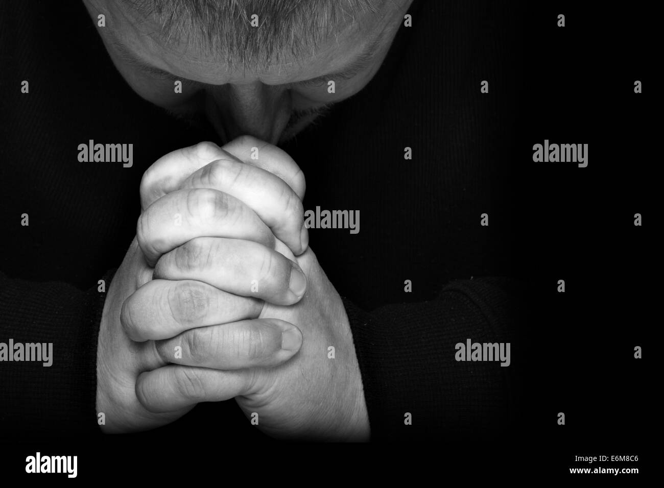 L'homme de prier pour quelque chose sur fond noir avec de l'espace pour le texte sur la droite Banque D'Images