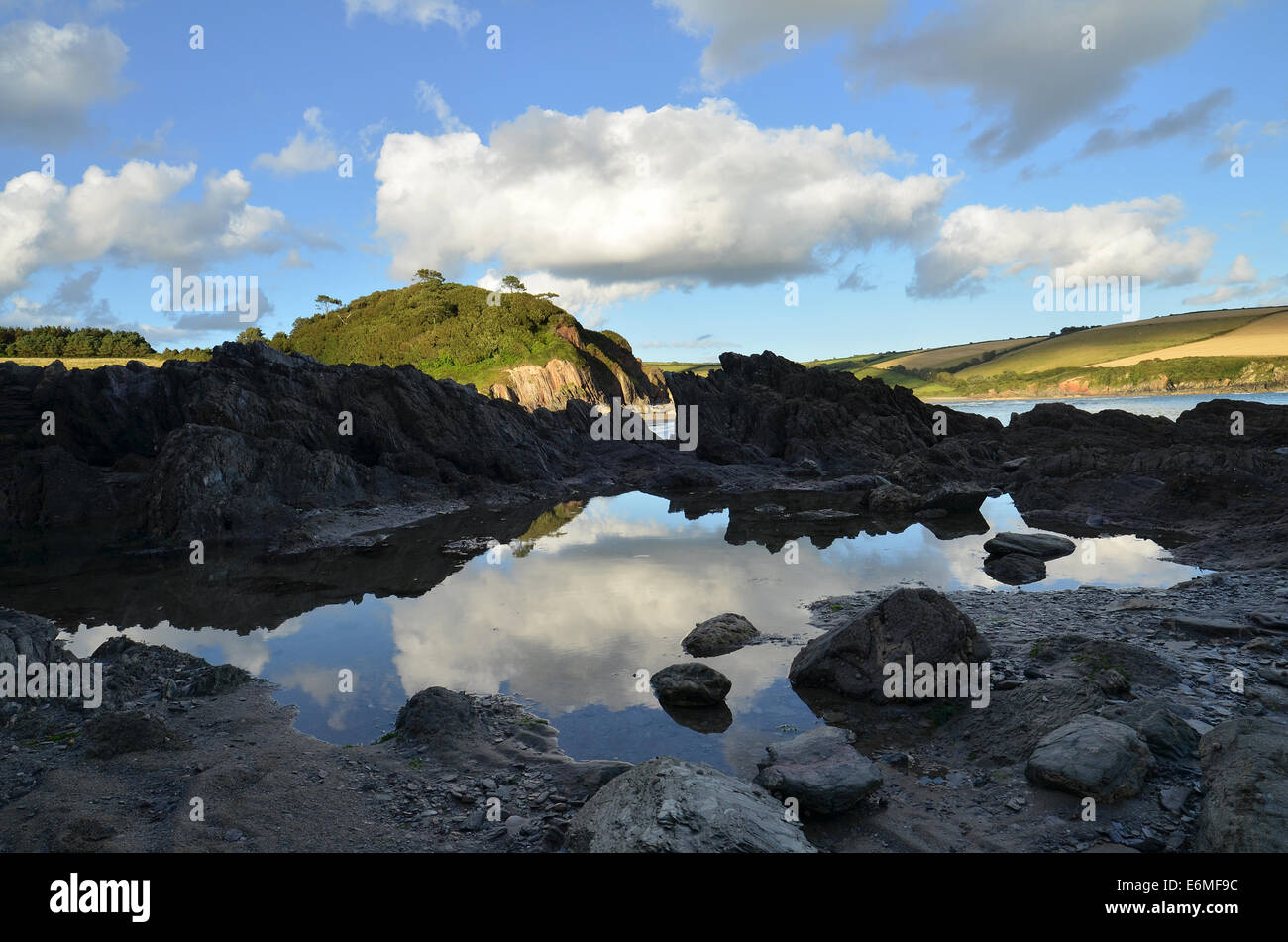 Rockpool sur Mothecombe beach reflétant le grand ciel et donnant sur les collines verdoyantes dans le Devon. Banque D'Images