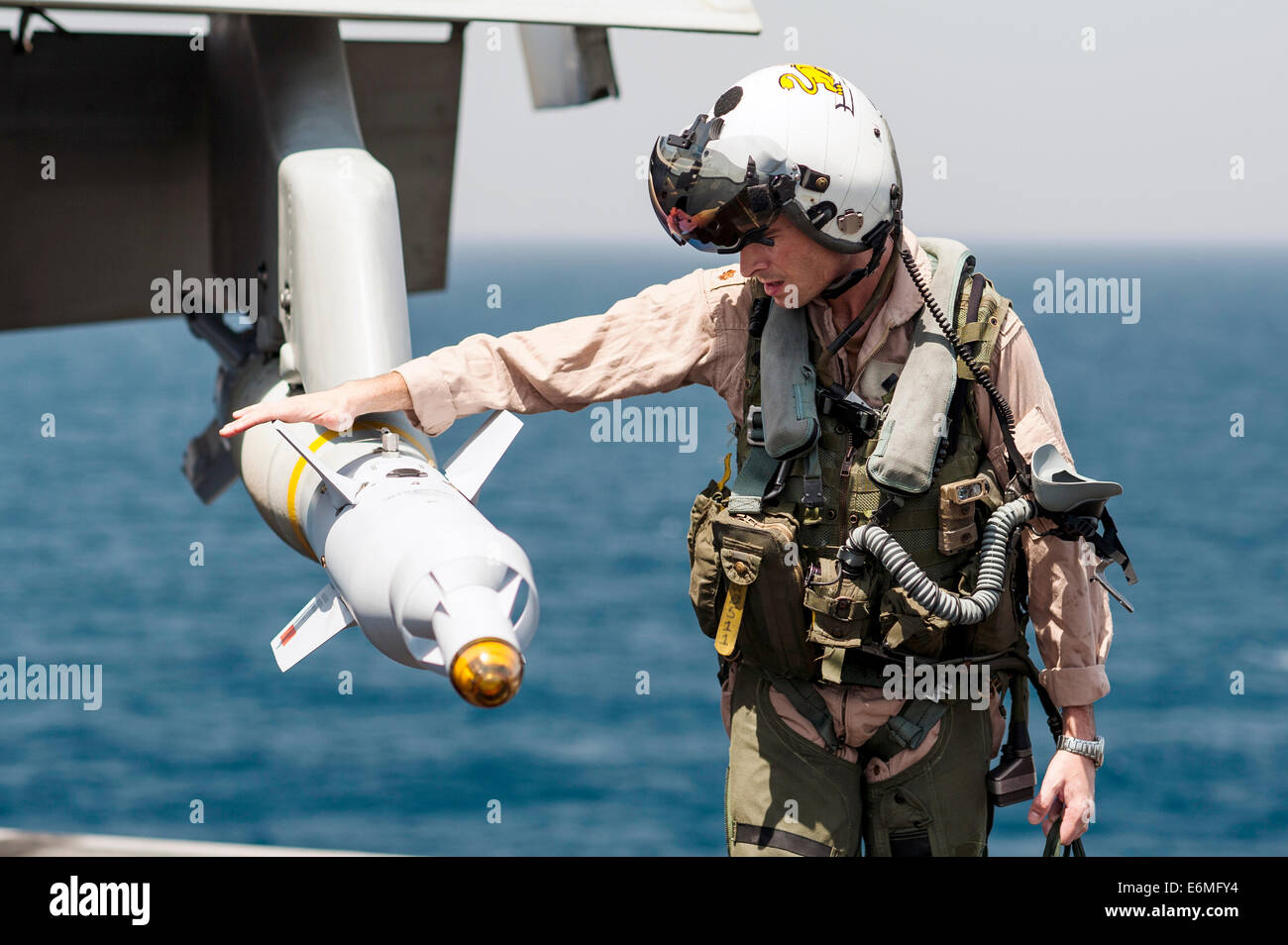 Un pilote de chasse de l'US Navy bombes guidées laser chèques pendant une visite pré-vol sur un F/A-18C Hornet avant le lancement d'une mission du porte-avions USS George H. W. Août 23, 2014 Bush dans le golfe Arabo-Persique. Les pilotes volent des frappes aériennes ciblées contre les extrémistes connus sous le nom de l'État islamique en Irak et au Levant. Banque D'Images