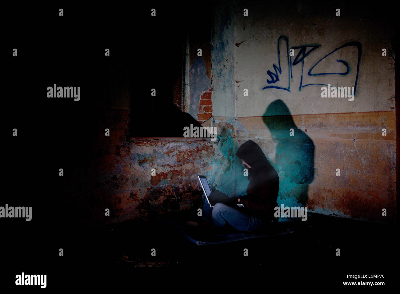 Pirate informatique femme assise avec un ordinateur portable dans le noir, dans un immeuble ancien Banque D'Images
