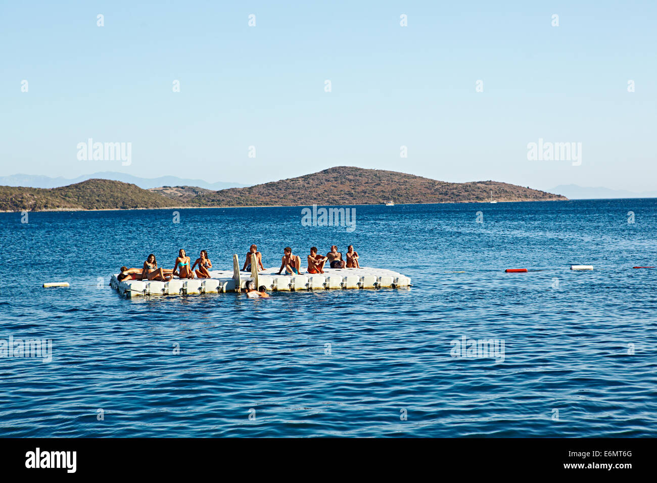 Les vacanciers à la dérive sur un radeau dans le bleu clair voir off Beyaz Beach Club, Bitez, Bodrum, Turquie Banque D'Images