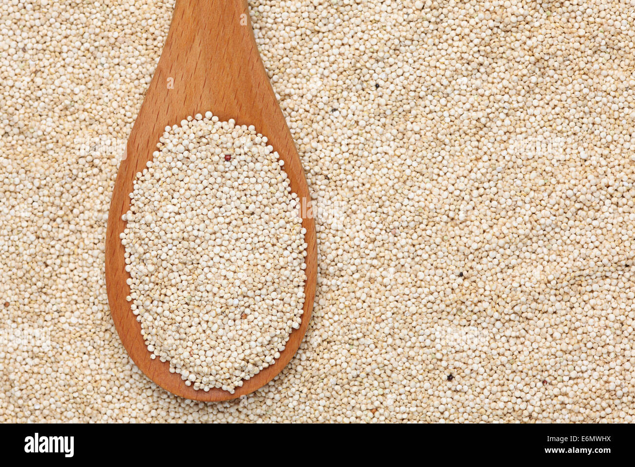 Les graines de quinoa dans une cuillère en bois sur les graines de quinoa background Banque D'Images