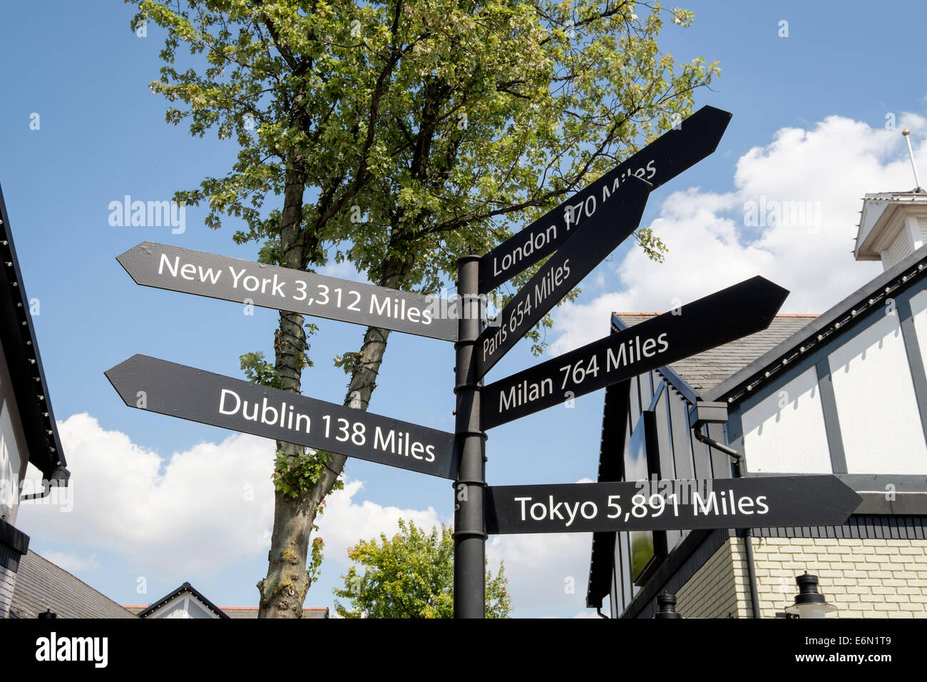 Les villes du monde en distances signpost Cheshire Oaks Shopping outlet. Ellesmere Port, Cheshire, Angleterre, Royaume-Uni, Angleterre Banque D'Images
