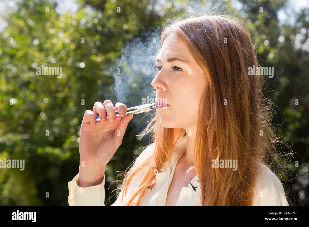 Jeune femme fumer une e-cigarette électronique Banque D'Images