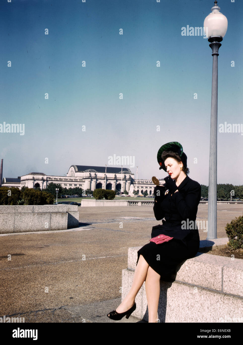 Woman putting sur son rouge à lèvres dans un parc avec la gare Union derrière elle, Washington, D.C., circa 1943 Banque D'Images