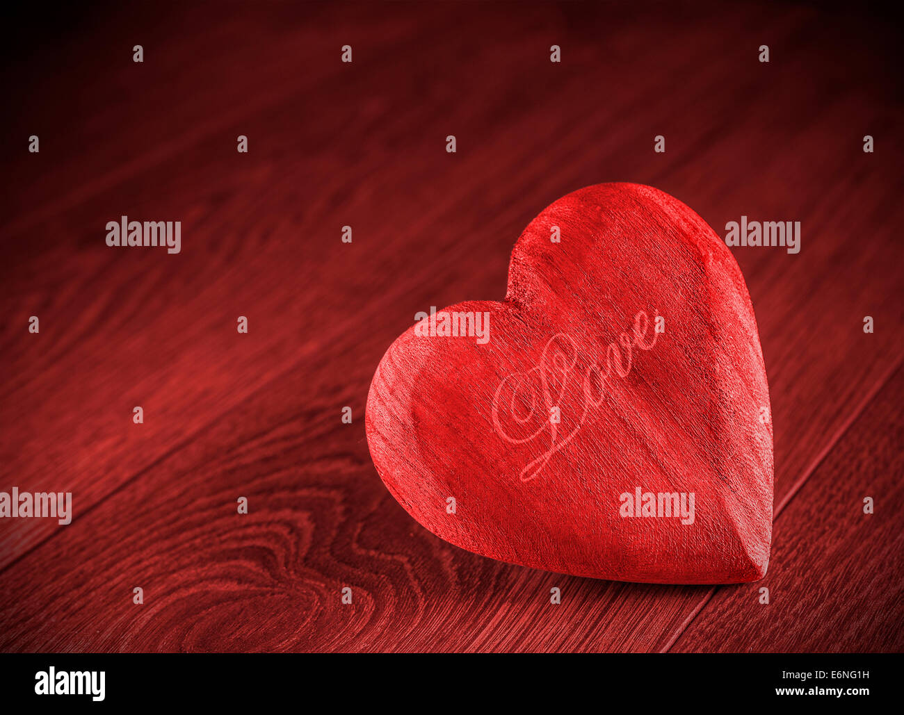 Coeur en bois rouge sur fond rouge. Banque D'Images