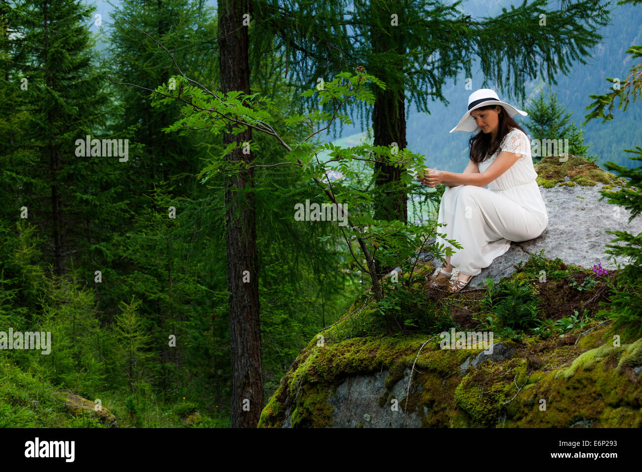 Femme en robe blanche avec white hat restant sur une grosse pierre dans la montagne Banque D'Images