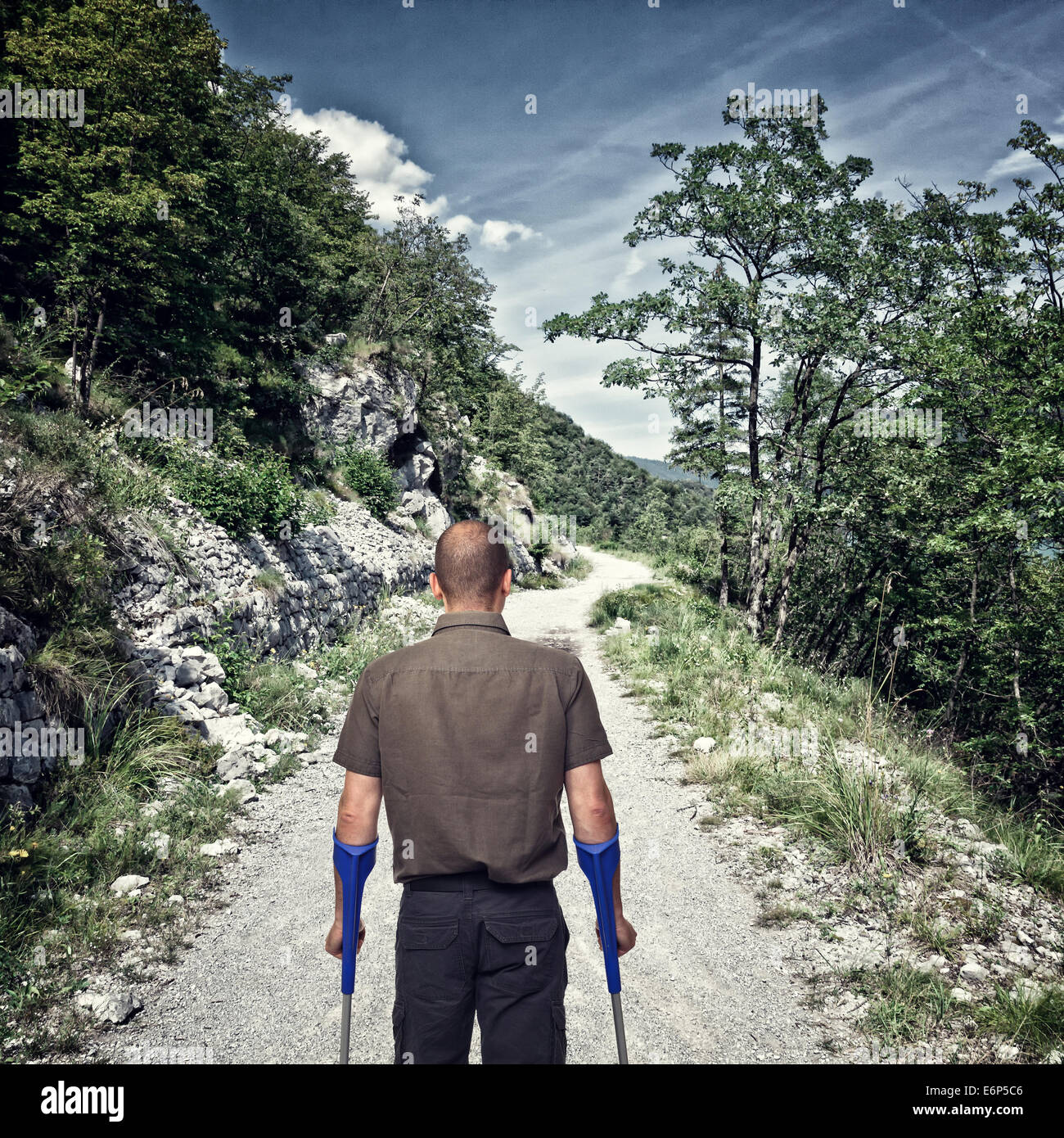 Homme avec des béquilles et route de montagne Banque D'Images