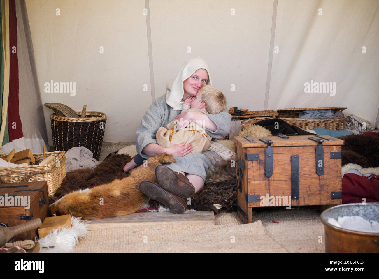 Mère berçant son fils Viking dans une tente à une reconstitution historique. UK Banque D'Images