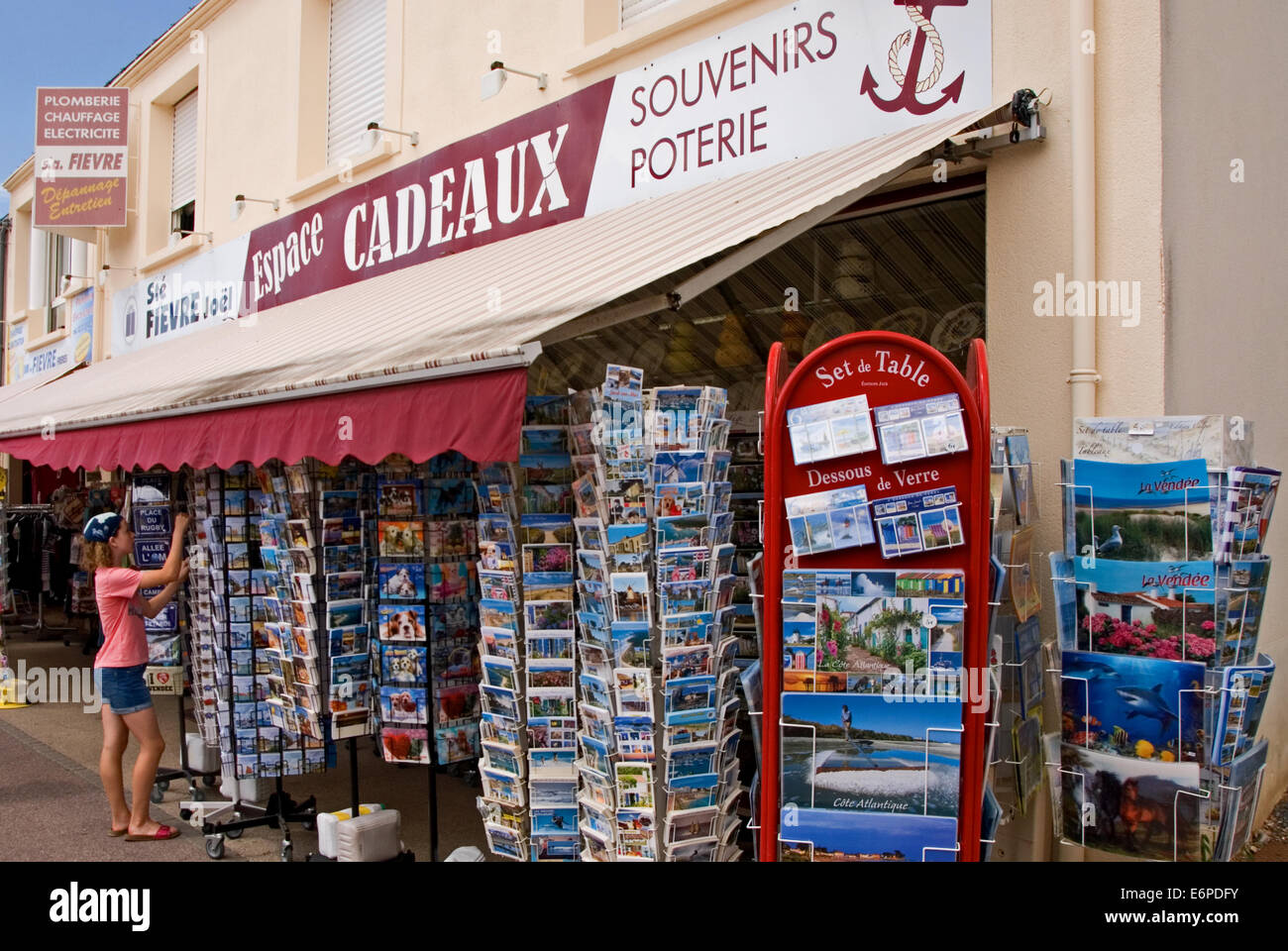 Jeune fille à la recherche de cartes postales à vendre à l'extérieur d'un magasin. Banque D'Images